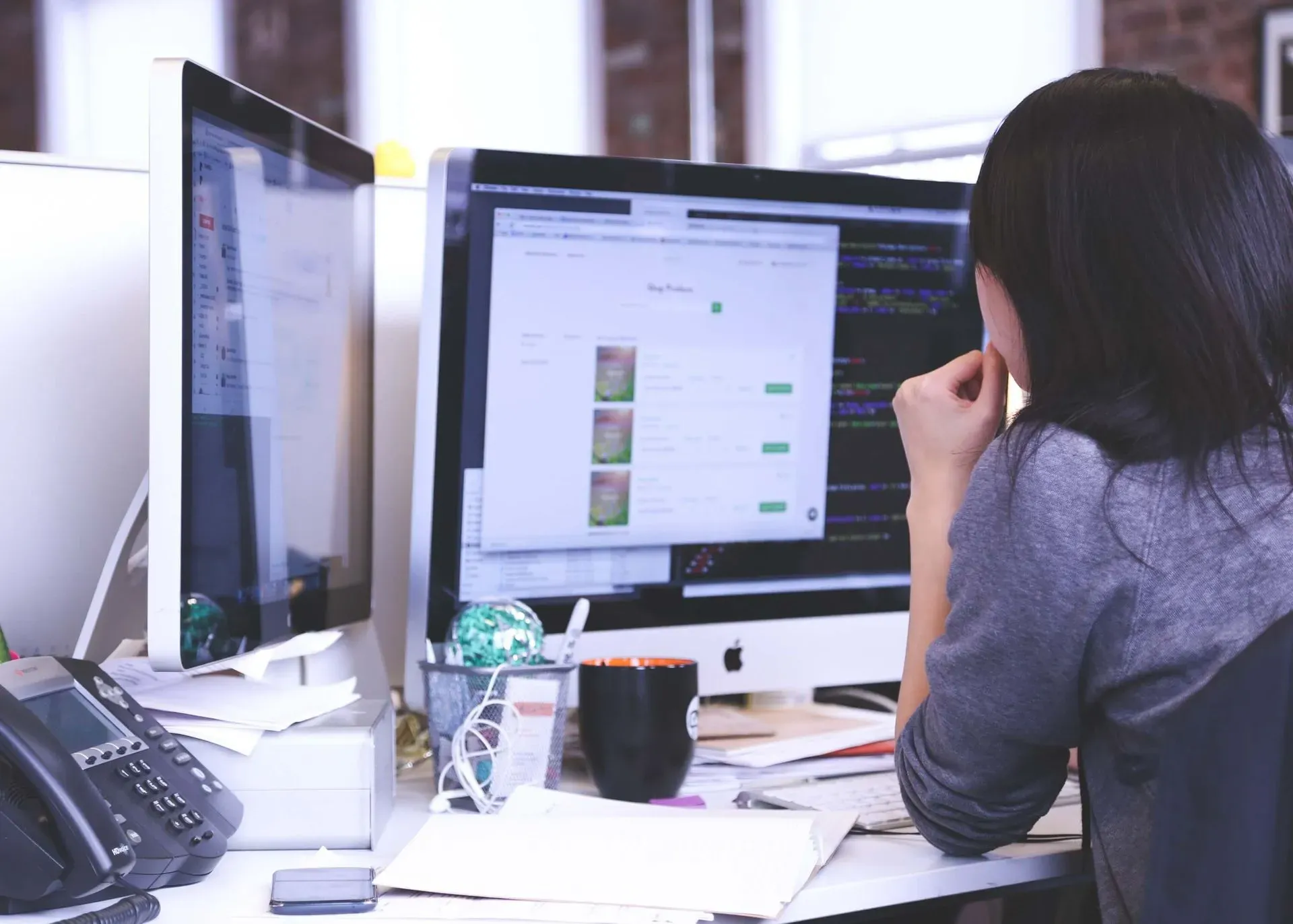 female working at her desk with code on the monitor